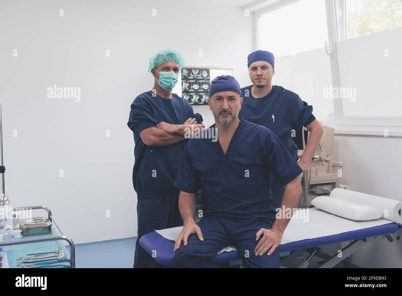 Multiethnischer orthopädischer Arzt vor seinem medizinischen Team sucht An der Kamera trägt Gesichtsmaske Stockfoto