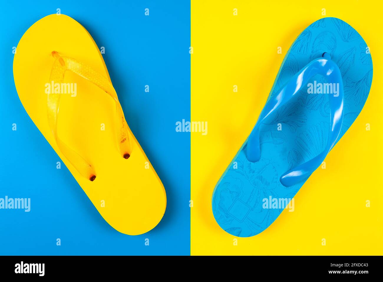 Blauer und gelber Flip-Flop aus Gummi auf blauem und gelbem Hintergrund Stockfoto