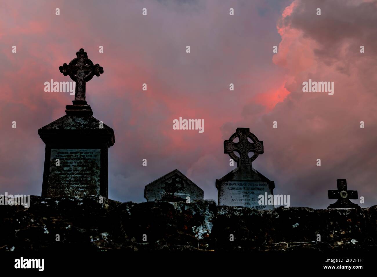 Graveyard Grabstein kreuzt Silhouetten, gegen einen dunklen stürmischen rötlichen Himmel Stockfoto