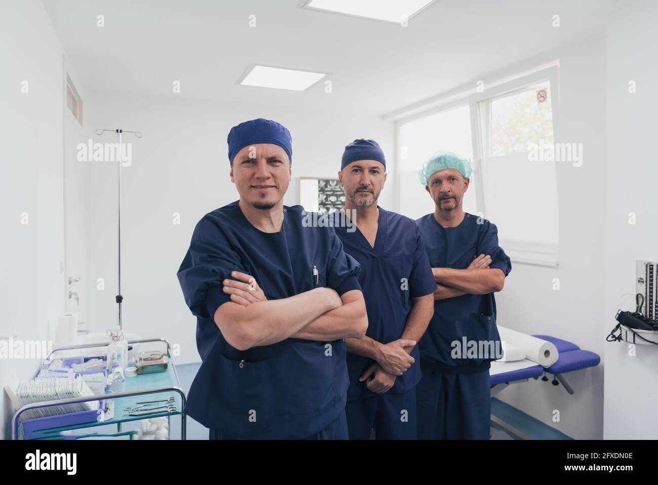 Multiethnischer orthopädischer Arzt vor seinem medizinischen Team sucht An der Kamera trägt Gesichtsmaske Stockfoto