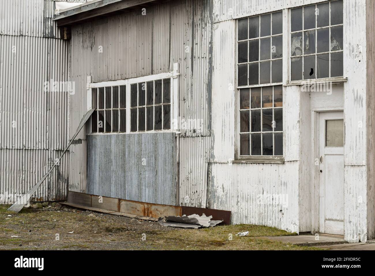 Die Fenster eines verlassenen Industriegebäudes spiegeln einen grauen und bewölkten Tag wider. Stockfoto