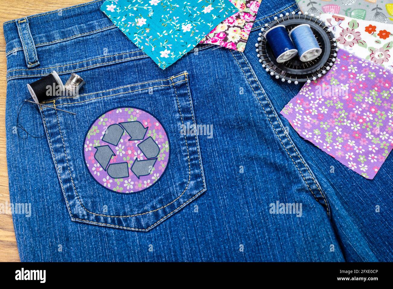 Recyceln Sie Kleidung Icon Patch auf Jeans, nachhaltige Mode sichtbare Ausbesserung Konzept, reparieren, recyceln, wiederverwenden Kleidung und Textilien Abfälle zu reduzieren Stockfoto