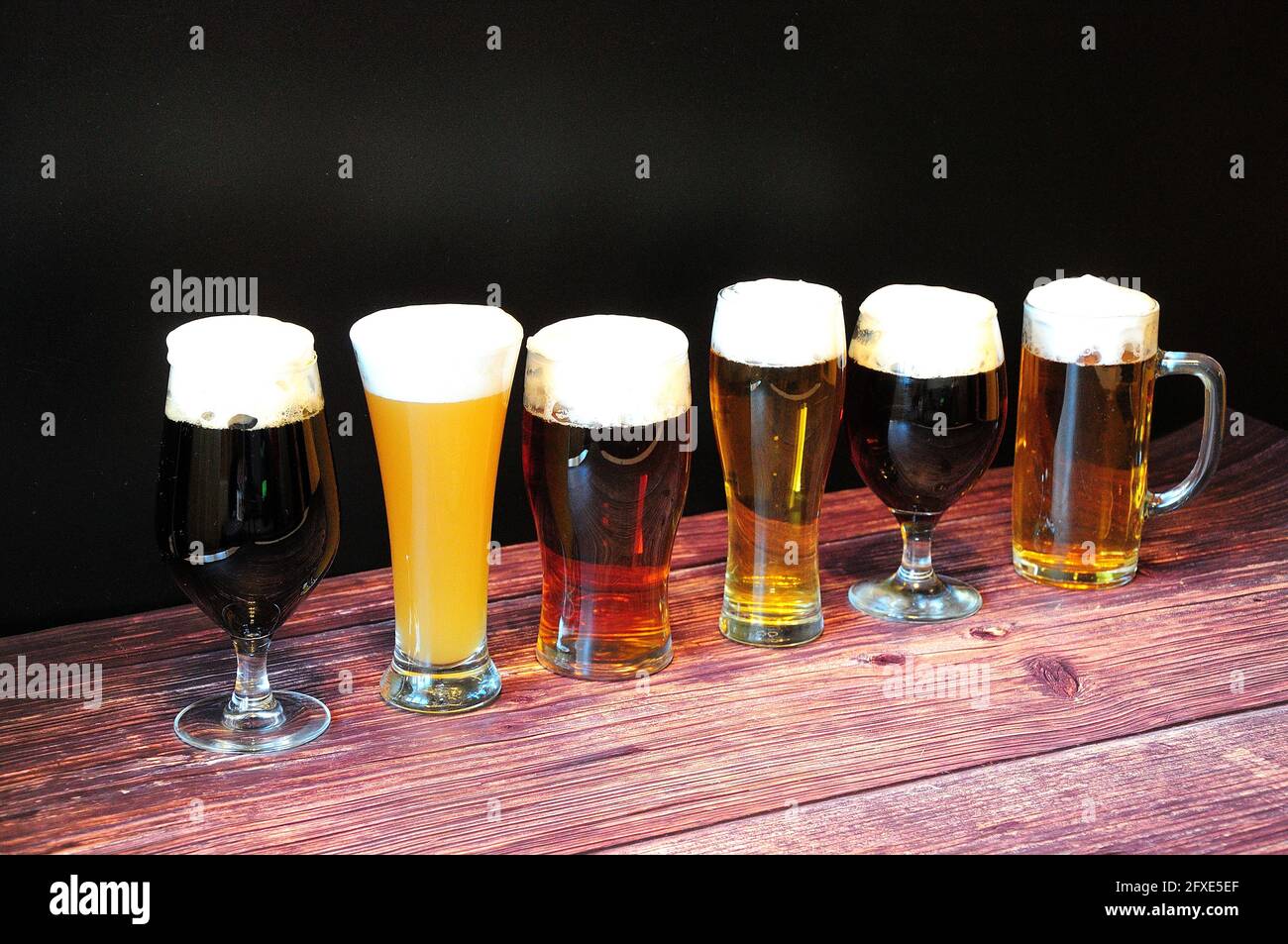 Sechs Gläser verschiedener Biersorten stehen auf einem Holztisch in einer Reihe. Nahaufnahme. Stockfoto
