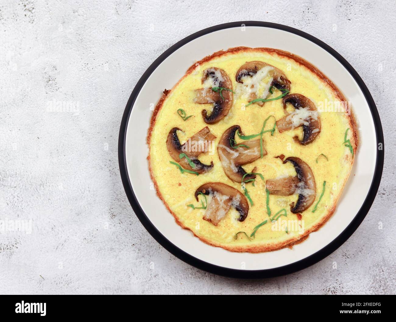 Omelette mit Pilzen auf einem runden Teller auf hellgrauem Hintergrund. Draufsicht, flach liegend Stockfoto