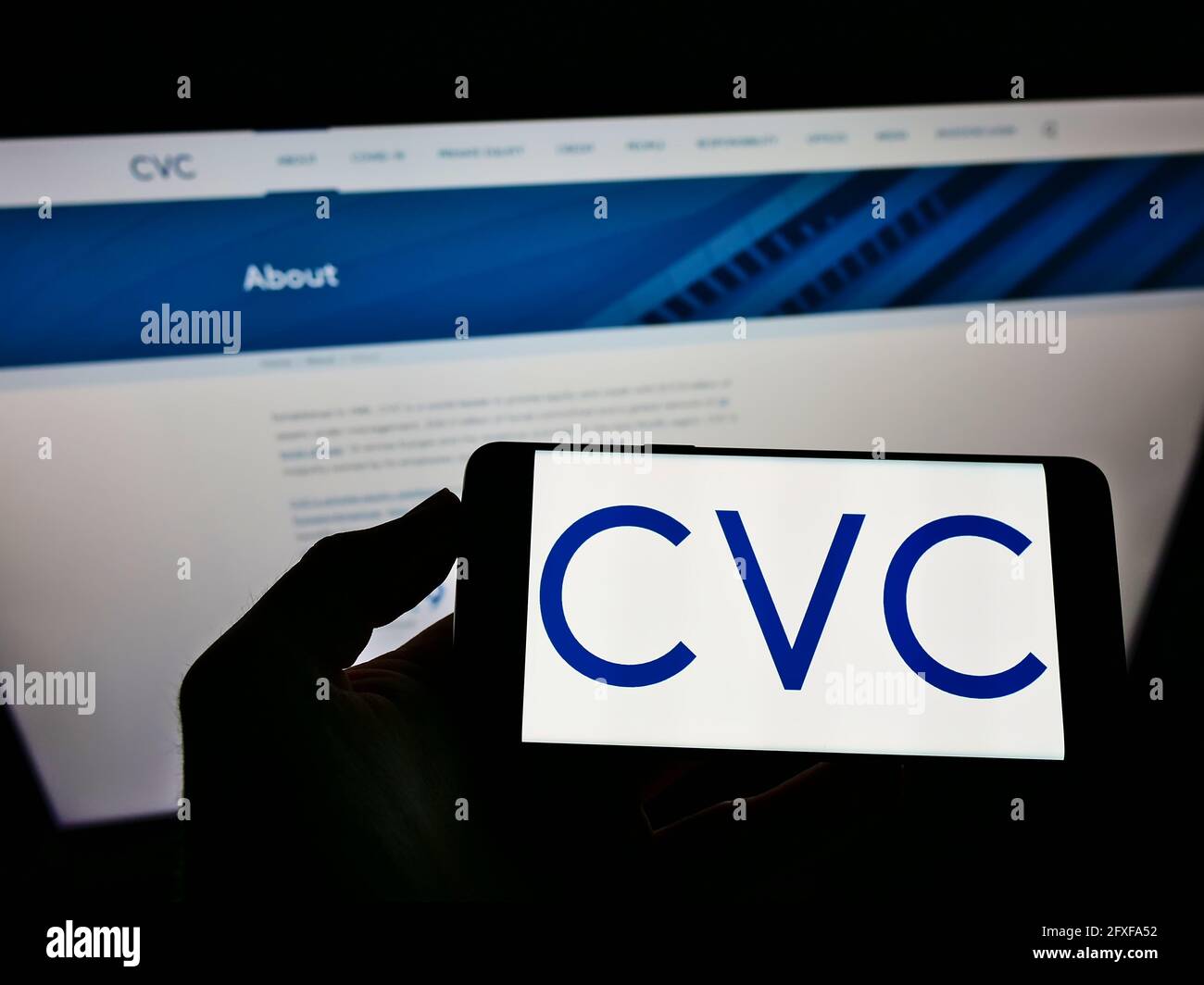 Person mit Mobiltelefon und Unternehmenslogo der Private-Equity-Gesellschaft CVC Capital Partners auf dem Bildschirm vor der Webseite. Konzentrieren Sie sich auf die Telefonanzeige. Stockfoto