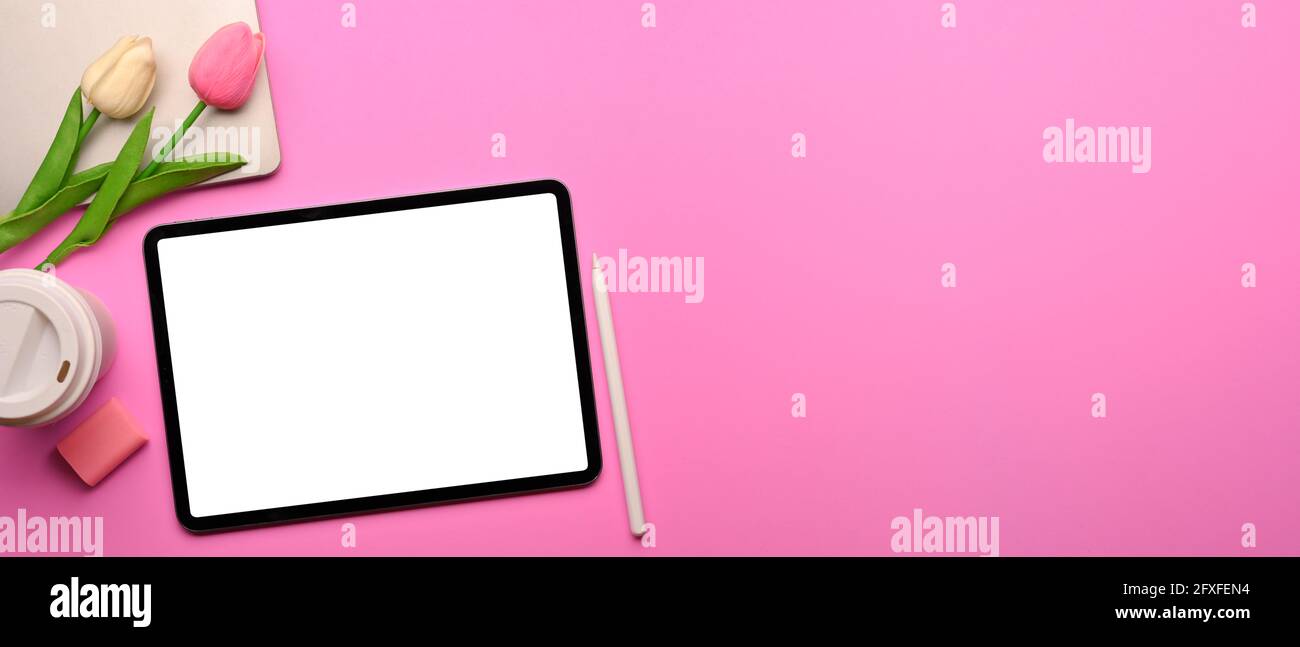 Draufsicht auf rosafarbenen, kreativen, flach auflegenen Arbeitsbereich mit digitalem Tablet, Verbrauchsmaterialien, Tulpenblumen und Kopierraum sowie Beschneidungspfad Stockfoto