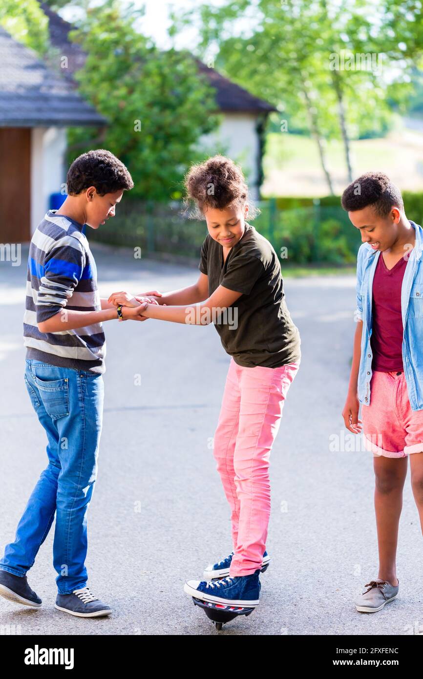 Drei schwarze Kinder, Jungen und Mädchen, Spielen zusammen mit Skateboard Stockfoto