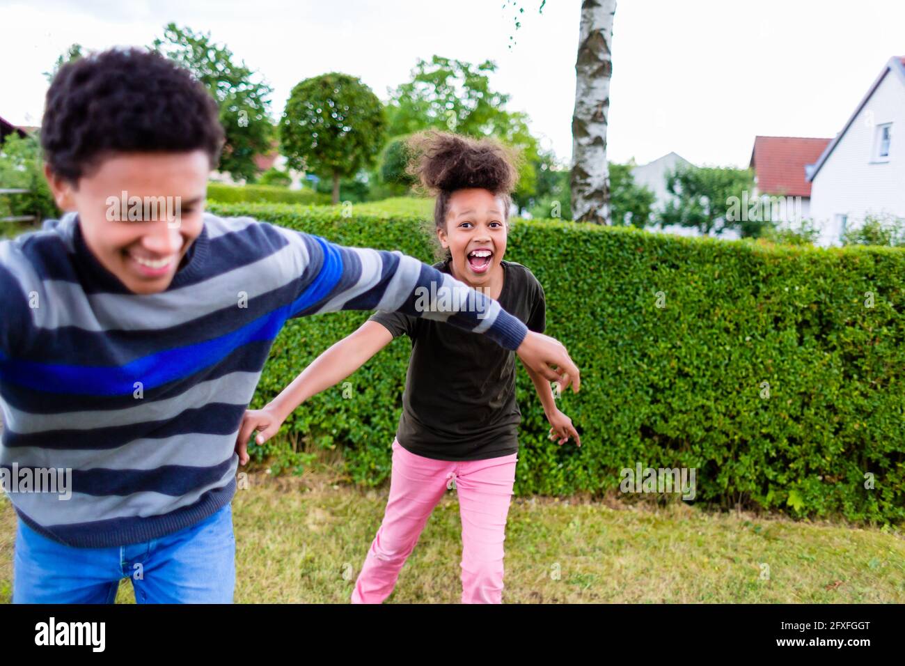 Geschwister, schwarze Junge und Mädchen, spielen im Garten Stockfoto