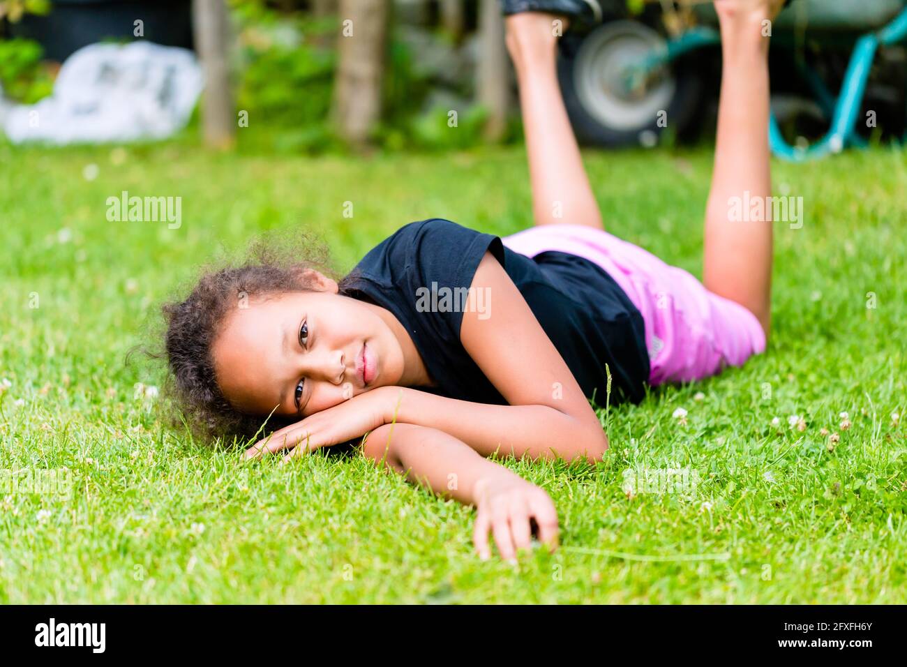 Afrikanische Mädchen spielen auf der Wiese vor der Lattenzaun um Rollen Stockfoto