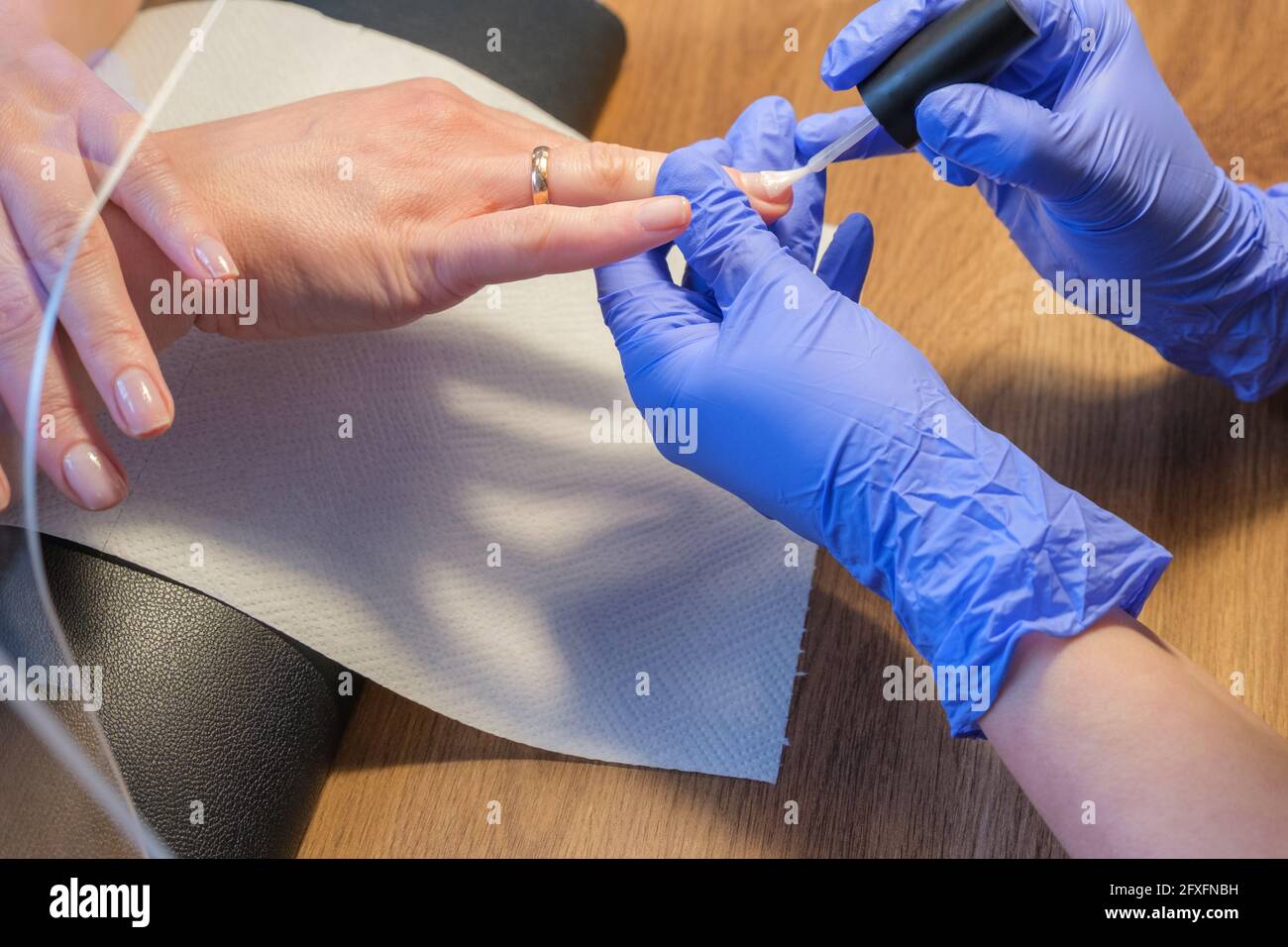Hände eines Manikuristen in schützenden medizinischen Handschuhen während der Arbeit. Prävention und Schutz vor Viren und Bakterien während einer Maniküre Stockfoto