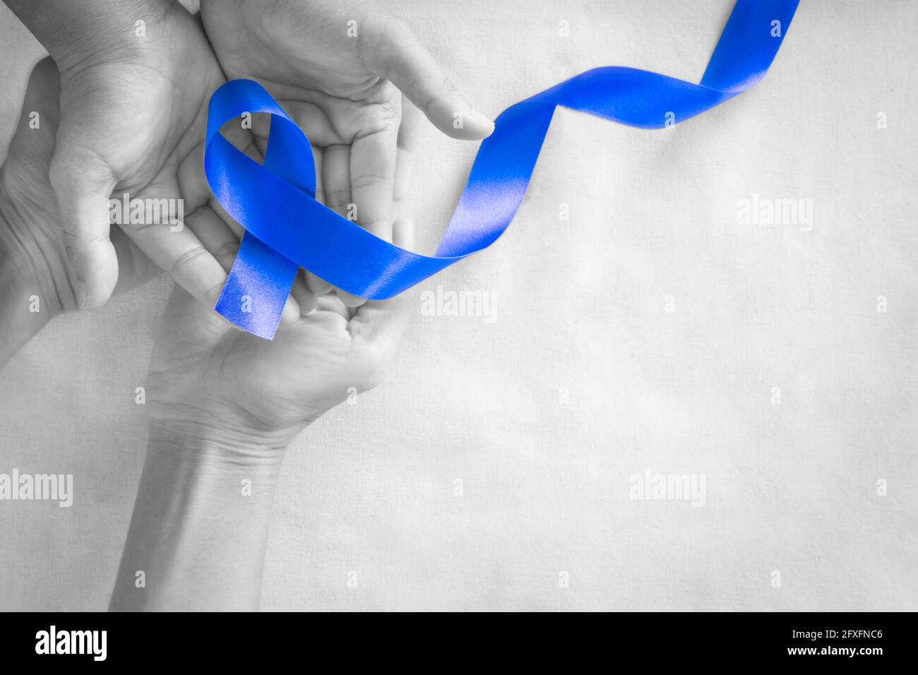 Hände mit tiefblauem Band auf weißem Stoff mit Kopierraum. Darmkrebs Bewusstsein, Colon Krebs der älteren Person und Welt Diabetes Tag, Chil Stockfoto