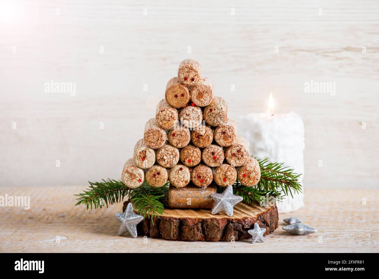 Handgemachte kreative Weihnachtsbaumdekoration mit Weinflaschen-Korken. Weiße Kerze brennt auf Holzhintergrund, viel Platz für Kopien. Upcycling. Stockfoto