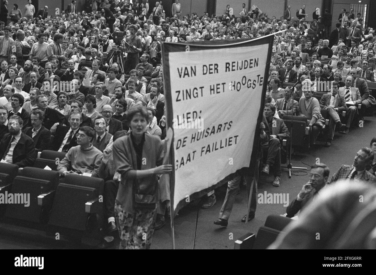 Treffen der Nationalen Vereinigung der Allgemeinpraktiker in der RAI in Amsterdam; Vorsitzender der Nationalen Vereinigung der Allgemeinpraktiker Regt mit Protestplakat, 13. Mai 1986, MENSCHLICHE DIENSTE, Treffen, Niederlande, Presseagentur des 20. Jahrhunderts, Foto, Nachrichten zum erinnern, Dokumentarfilm, historische Fotografie 1945-1990, visuelle Geschichten, Menschliche Geschichte des zwanzigsten Jahrhunderts, Momente in der Zeit festzuhalten Stockfoto