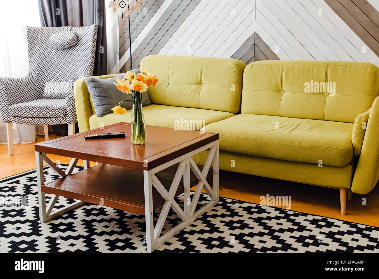 Wohnzimmer mit hellgrünem Sofa und Couchtisch aus Holz Mit Blumen Stockfoto