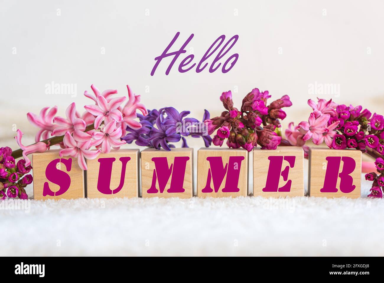 Worte Hello Summer Frische Blumen auf weißem, flauschigen Stoff Stockfoto