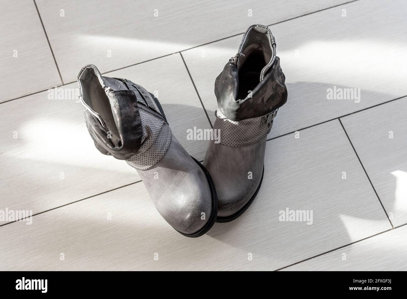 Stylische Stiefeletten mit niedrigen Absätzen stehen auf hellem Boden Stockfoto