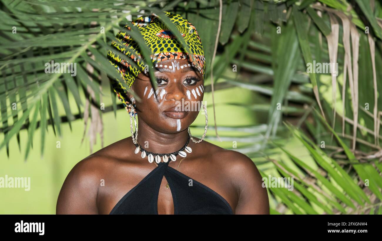Afrikanische Frau im Dschungel mit natürlicher Abendsonne im tropischen Teil von Aburi Ghana Westafrika. Bemalt mit Kofferraumfarbe auf dem Gesicht und dem Typ Stockfoto