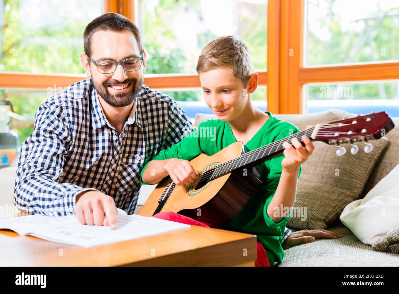 Vater und Sohn Gitarre spielen zu Hause, gemeinsames Musizieren Stockfoto