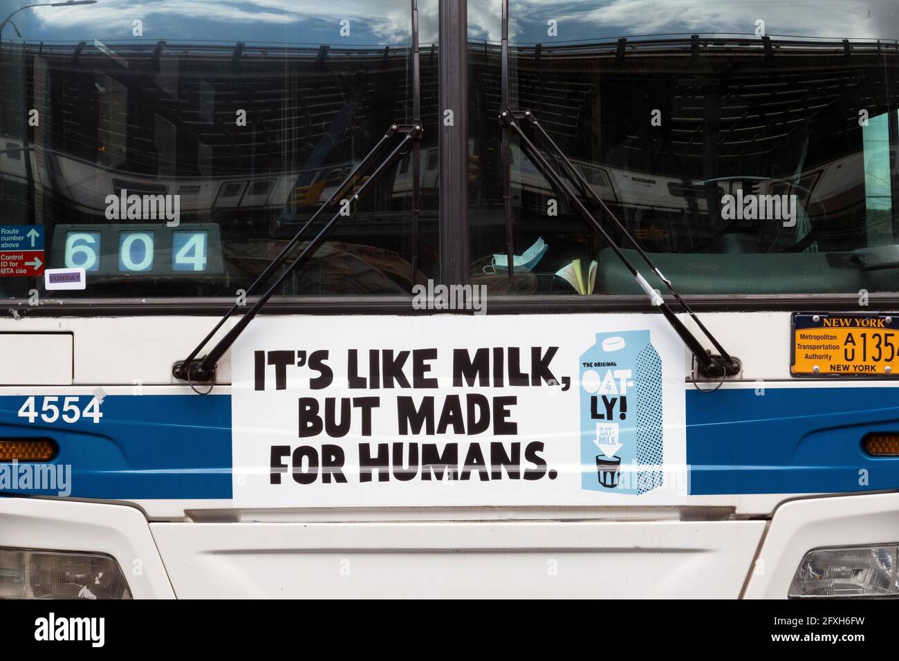 Eine schrullige Oatly Hafermilch-Anzeige auf der Vorderseite eines New York City-Busses, die sagt, es ist wie Milch, aber Mad für Menschen. In Brooklyn, New York City. Stockfoto