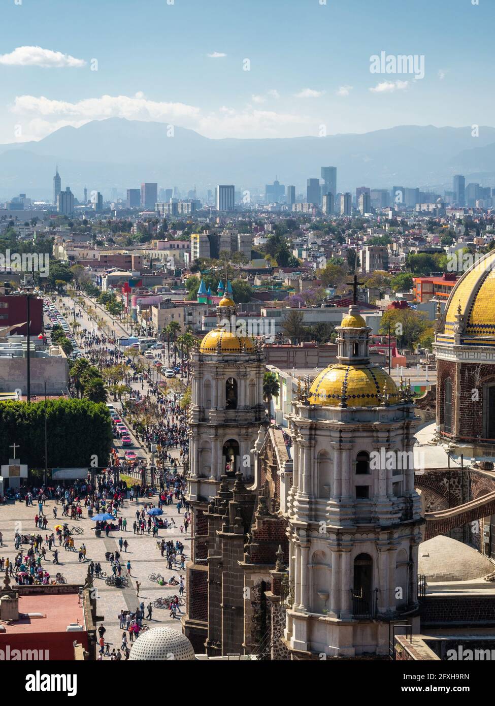 Mexiko-Stadt, Mexiko, historische Wahrzeichen Basilika unserer Lieben Frau von Guadalupe mit Skyline von Mexiko-Stadt an einem sonnigen Tag. Stockfoto