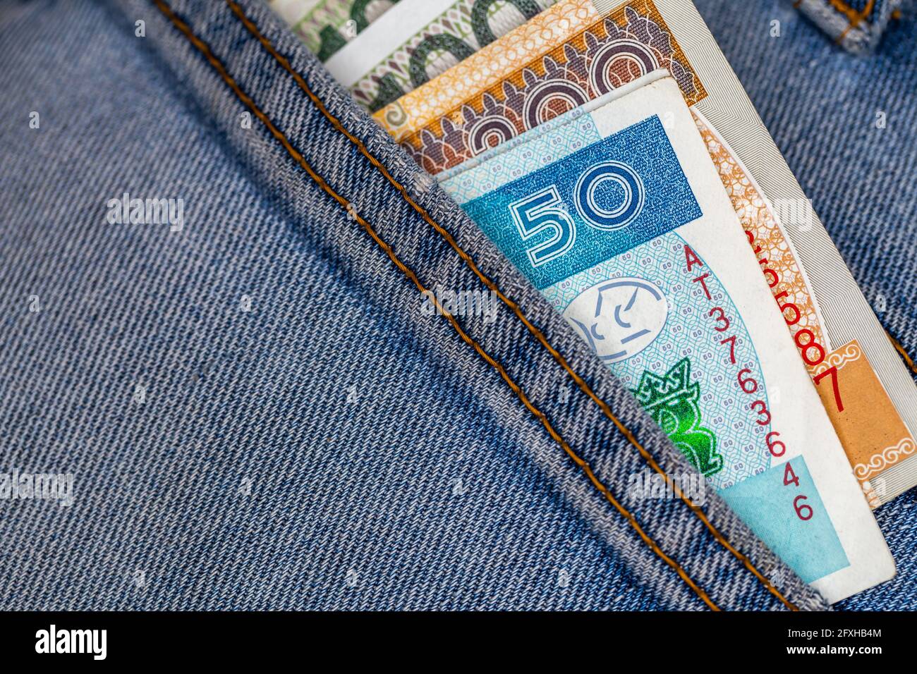 Viele polnische Scheine ragen aus der Gesäßtasche der Denim-Hose. Foto aufgenommen unter künstlichem, weichem Licht Stockfoto