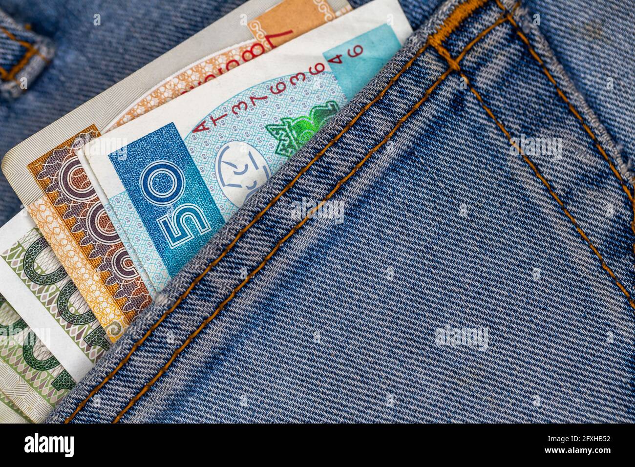 Viele polnische Scheine ragen aus der Gesäßtasche der Denim-Hose. Foto aufgenommen unter künstlichem, weichem Licht Stockfoto
