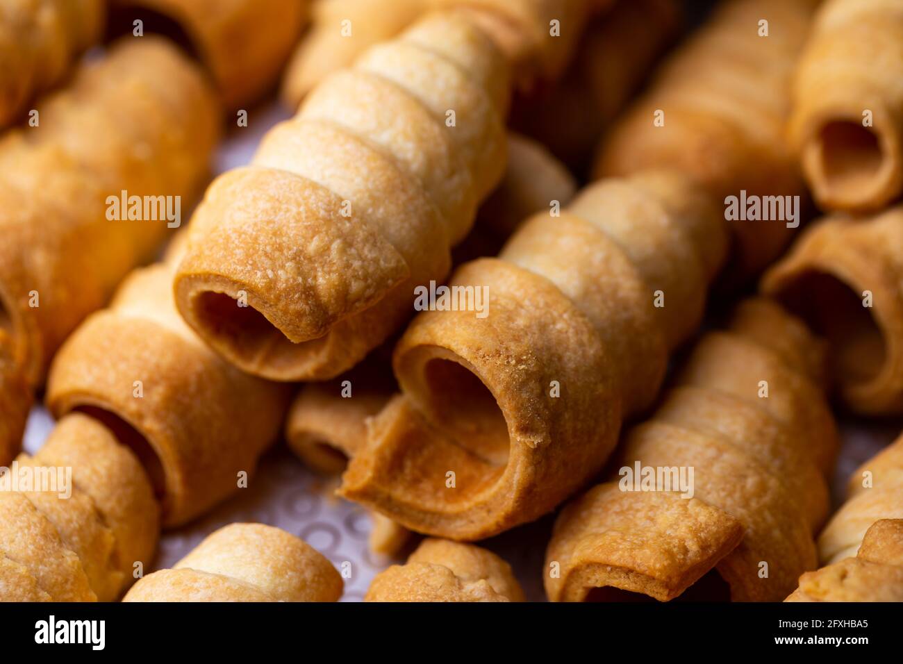 Viele süße hausgemachte Süßwarenröhrchen, die mit Creme gefüllt werden können. Foto aufgenommen unter weichem Kunstlicht. Stockfoto