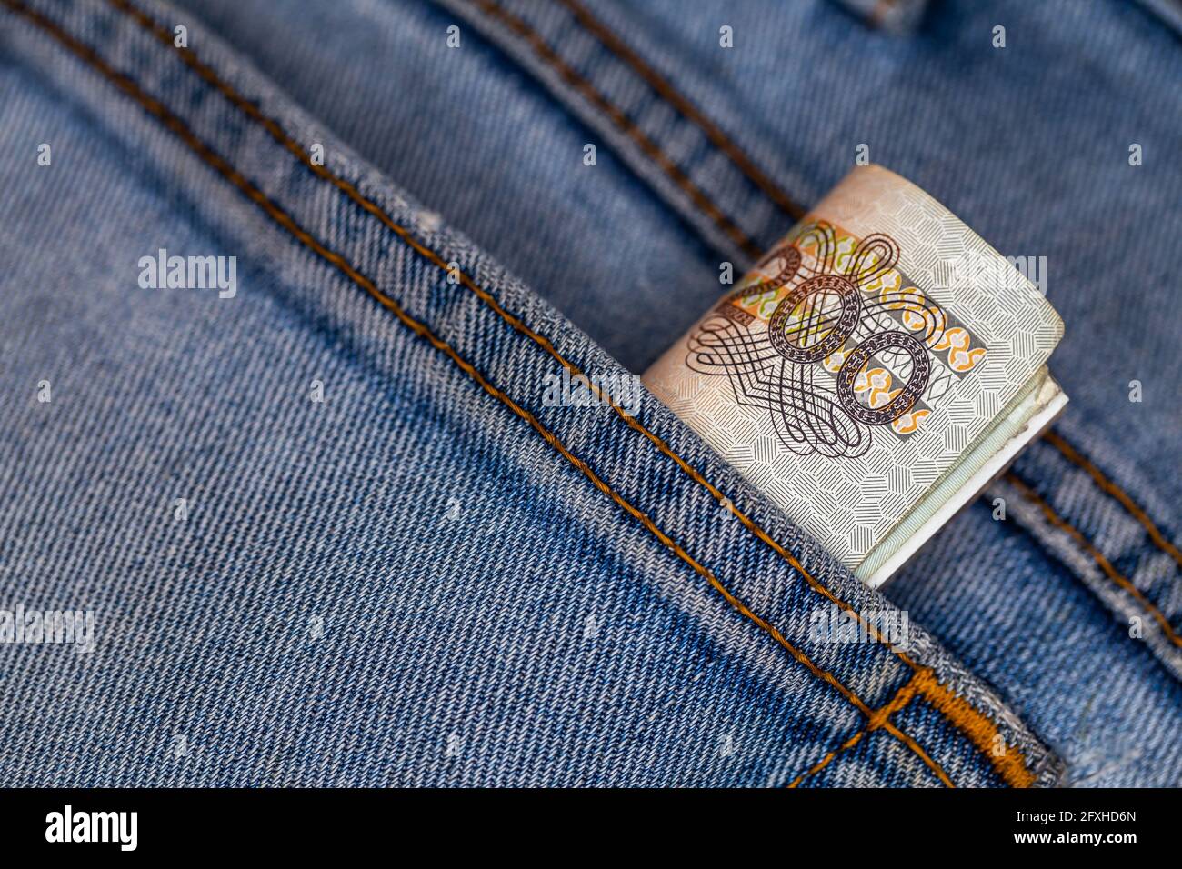 Viele polnische 200-pln-Banknoten ragen aus der Gesäßtasche der Denim-Hose. Foto aufgenommen unter künstlichem, weichem Licht Stockfoto