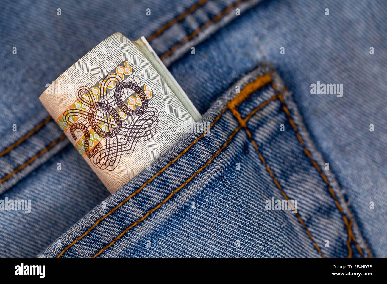 Viele polnische 200-pln-Banknoten ragen aus der Gesäßtasche der Denim-Hose. Foto aufgenommen unter künstlichem, weichem Licht Stockfoto