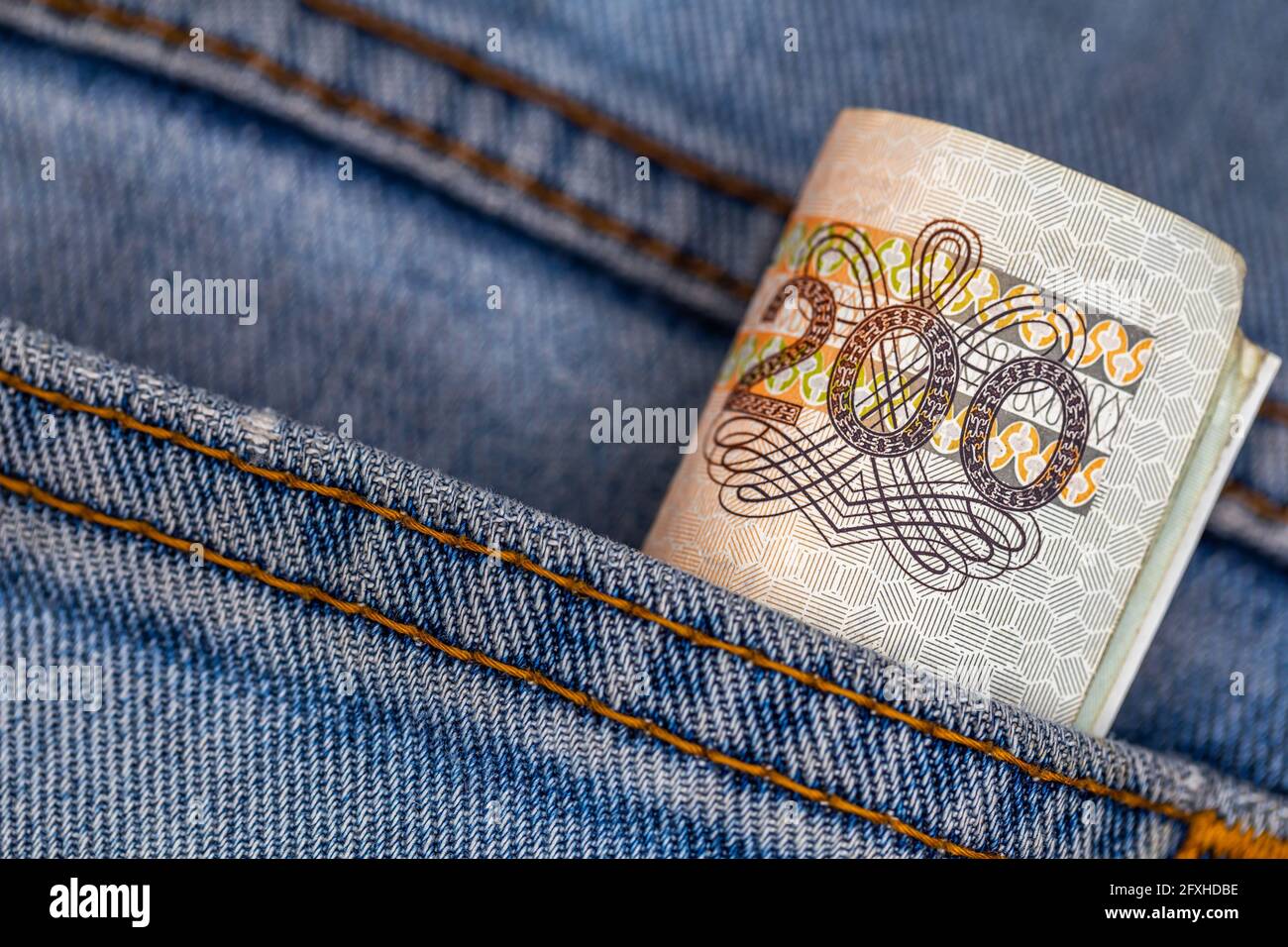 Viele polnische 200-pln-Banknoten ragen aus der Gesäßtasche der Denim-Hose. Foto aufgenommen unter künstlichem, weichem Licht Stockfoto