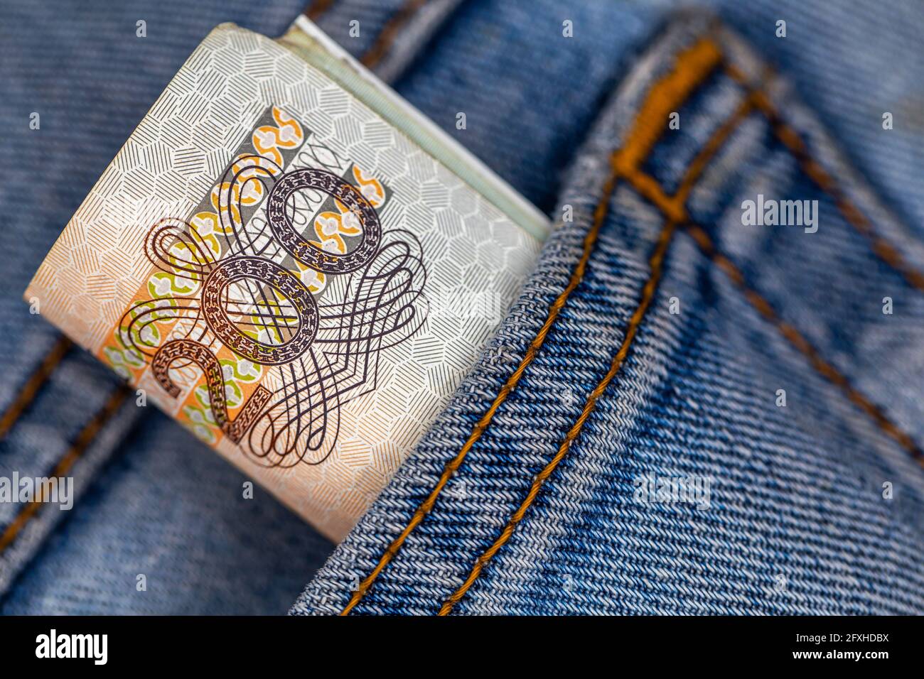Viele polnische 200-pln-Banknoten ragen aus der Gesäßtasche der Denim-Hose. Foto aufgenommen unter künstlichem, weichem Licht Stockfoto