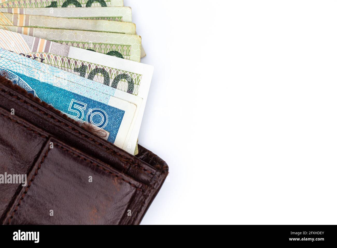 Viele polnische Banknoten ragen aus einer braunen Ledertasche. Foto aufgenommen unter künstlichem, weichem Licht, Objekt isoliert auf weißem Hintergrund Stockfoto