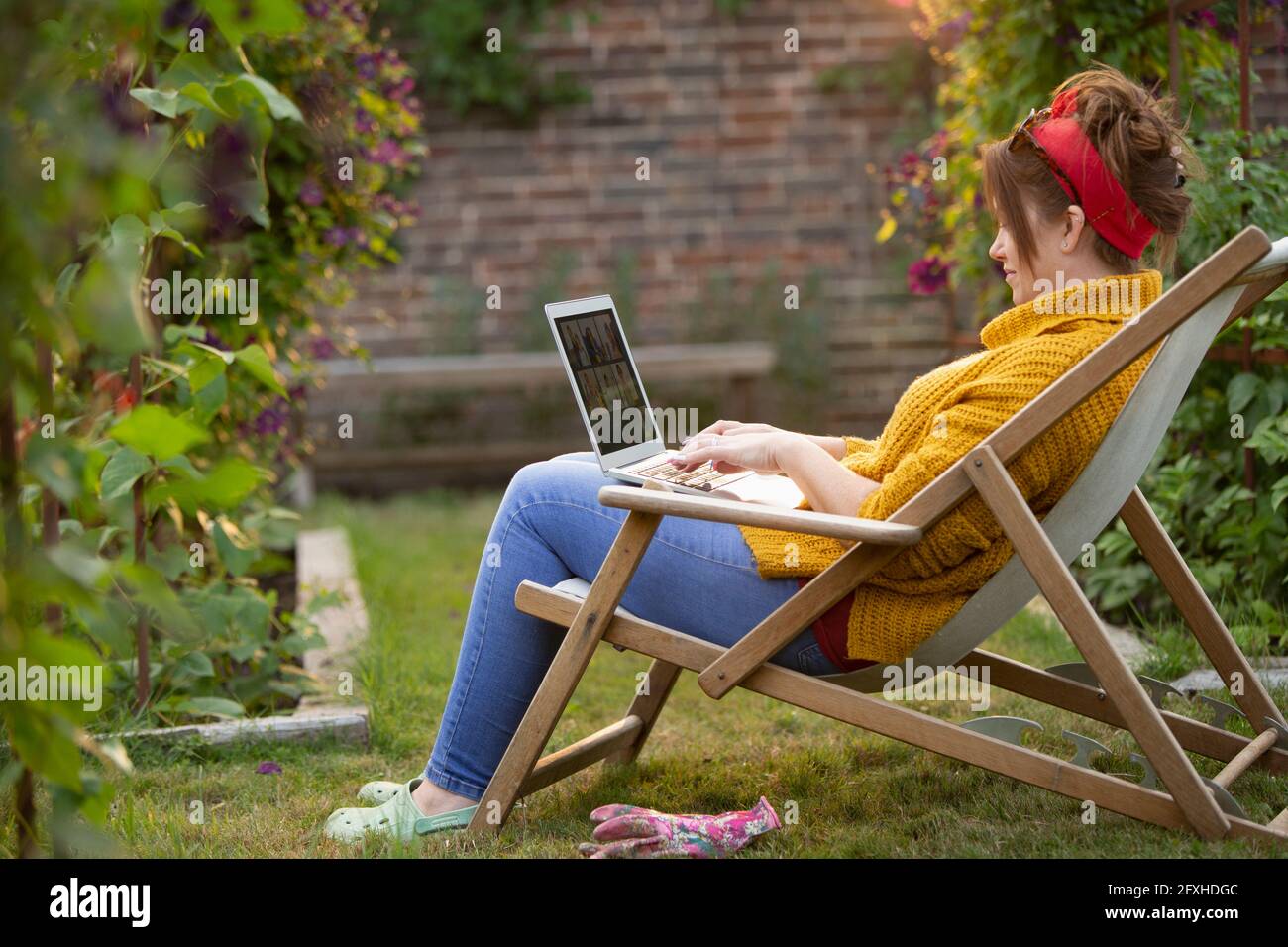 Frau, die im Garten am Laptop arbeitet Stockfoto