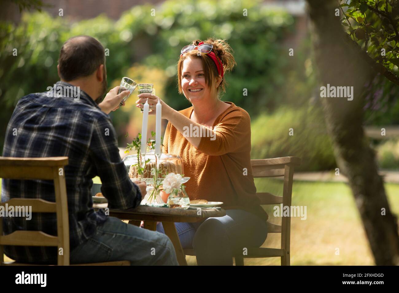 Glückliches Paar, das sich am sonnigen Gartentisch festklebte Stockfoto