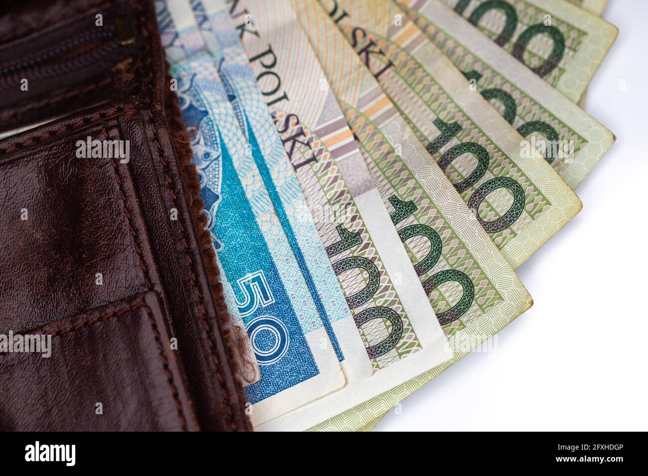 Viele polnische Banknoten ragen aus einer braunen Ledertasche. Foto aufgenommen unter künstlichem, weichem Licht, Objekt isoliert auf weißem Hintergrund Stockfoto