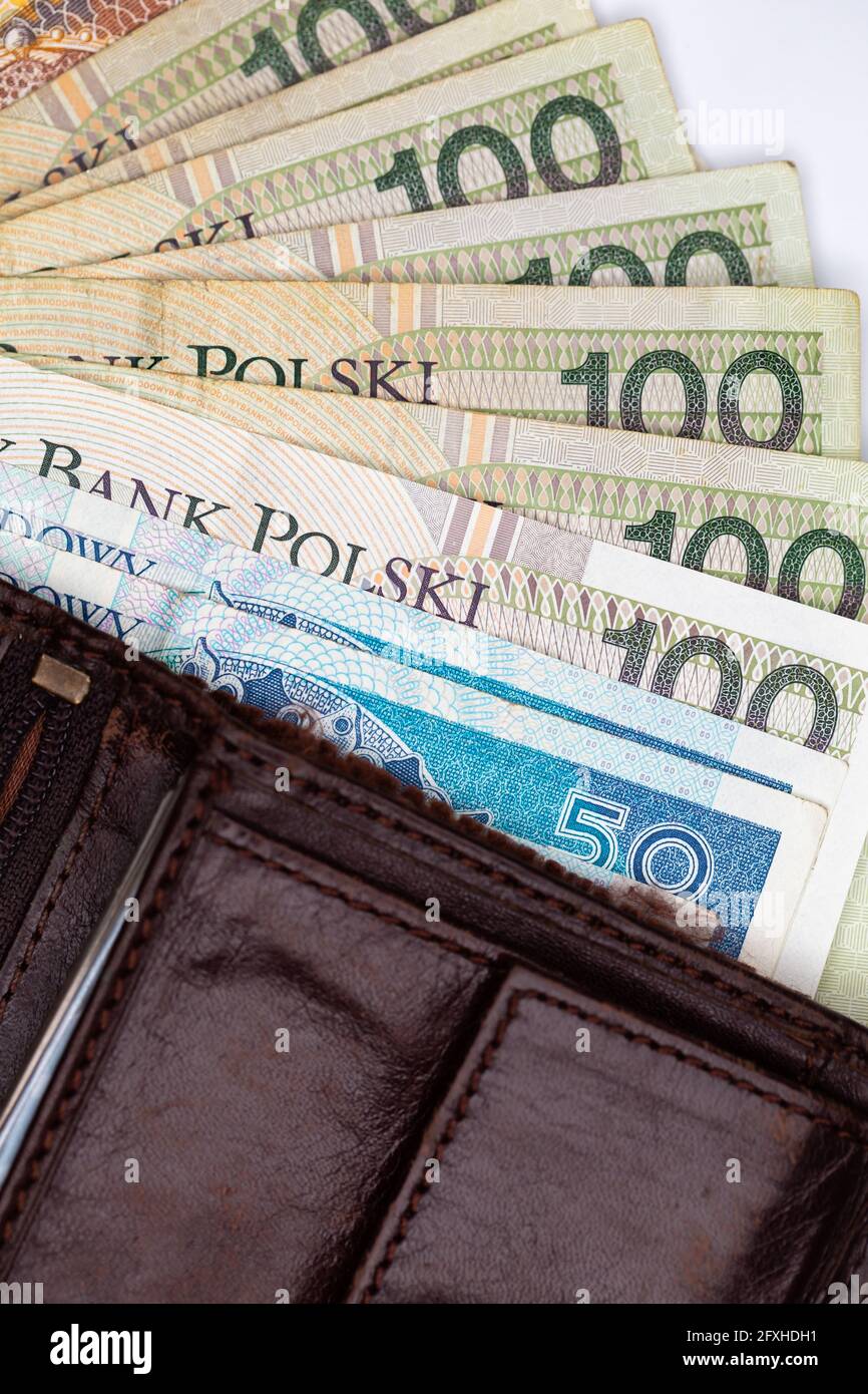 Viele polnische Banknoten ragen aus einer braunen Ledertasche. Foto aufgenommen unter künstlichem, weichem Licht, Objekt isoliert auf weißem Hintergrund Stockfoto