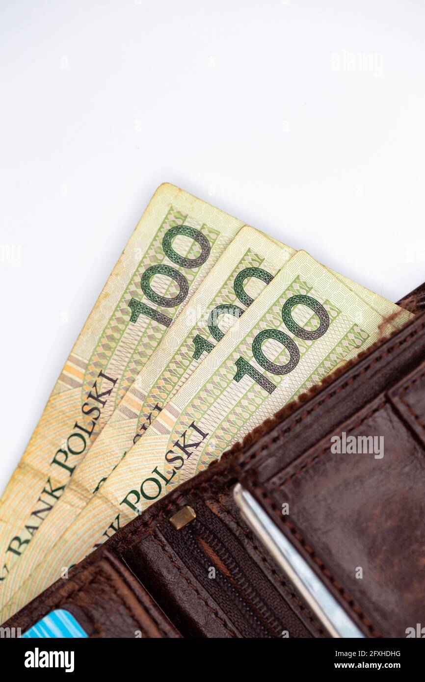 Viele polnische Banknoten ragen aus einer braunen Ledertasche. Foto aufgenommen unter künstlichem, weichem Licht, Objekt isoliert auf weißem Hintergrund Stockfoto