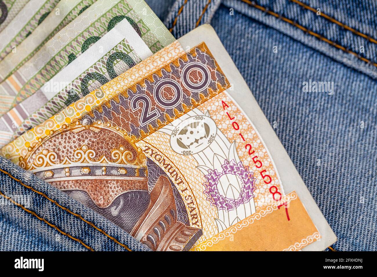 Viele polnische Scheine ragen aus der Gesäßtasche der Denim-Hose. Foto aufgenommen unter künstlichem, weichem Licht Stockfoto
