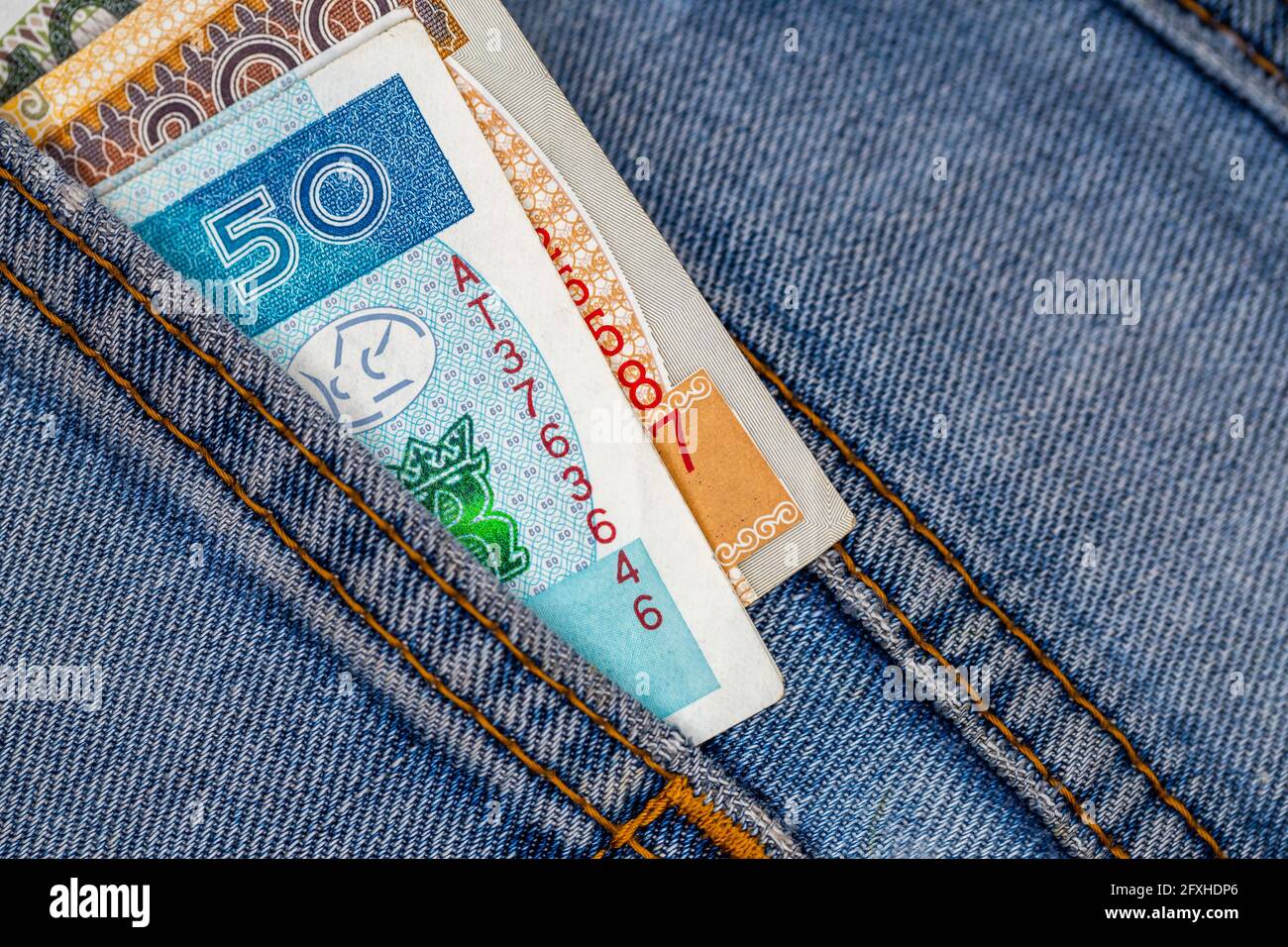 Viele polnische Scheine ragen aus der Gesäßtasche der Denim-Hose. Foto aufgenommen unter künstlichem, weichem Licht Stockfoto