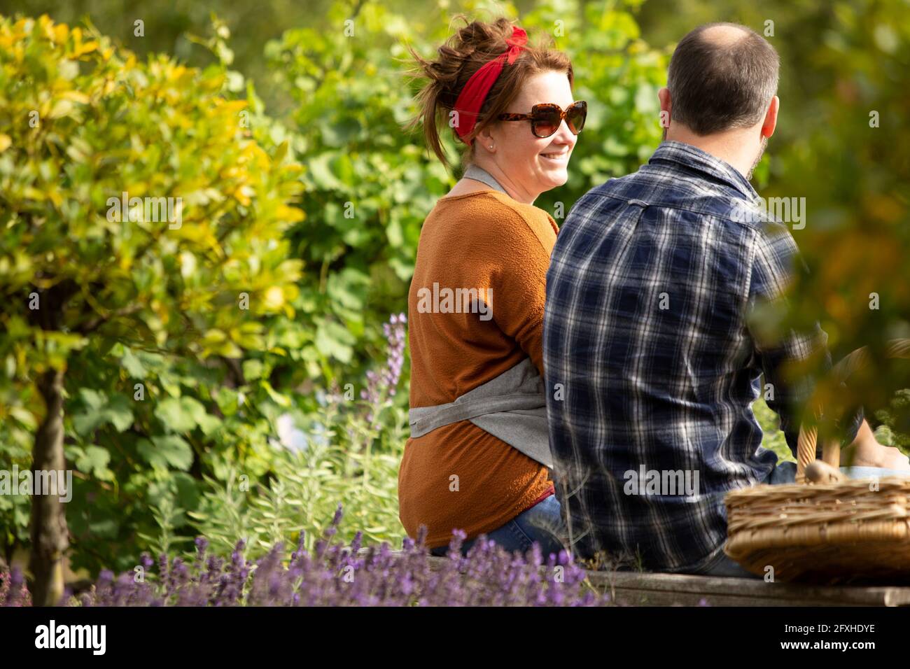 Pärchen, die eine Pause von der Gartenarbeit im sonnigen Sommerhof machen Stockfoto