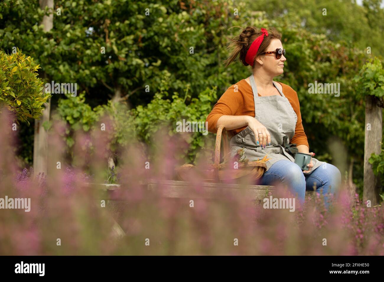 Frau in Sonnenbrillen, die eine Pause von der Gartenarbeit im Sommergartenhof nimmt Stockfoto