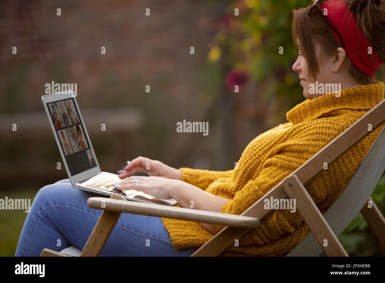 Frau mit Laptop in einem Rasenstuhl Stockfoto