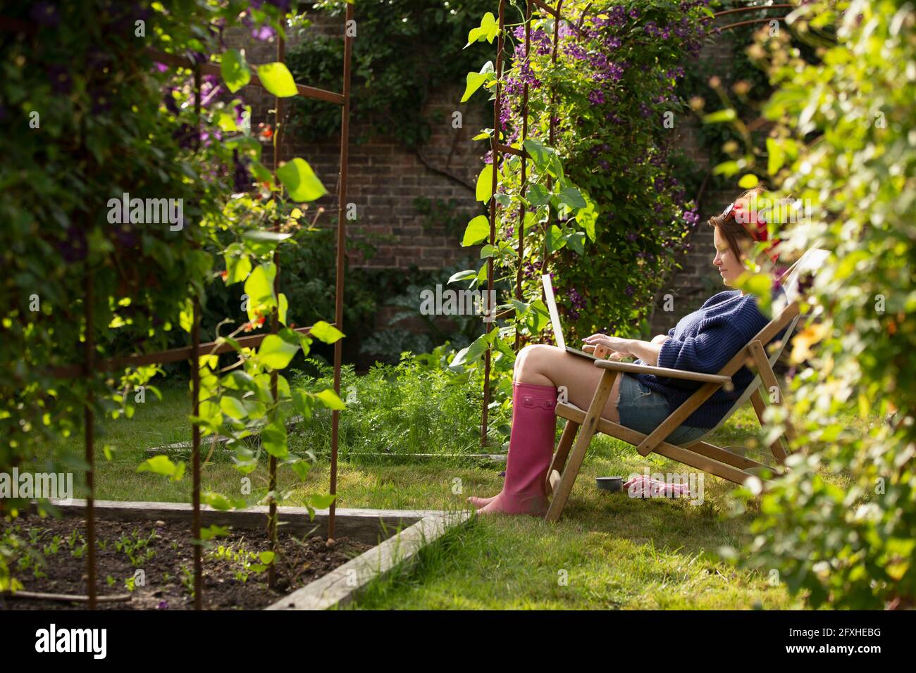 Frau mit Laptop im sonnigen Sommergarten Stockfoto