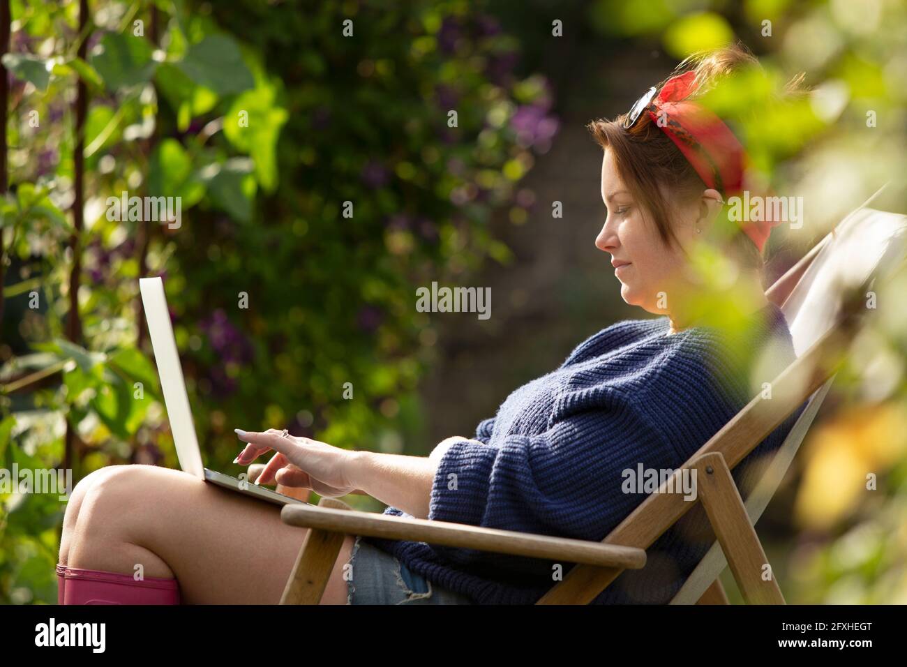 Frau mit Laptop im sonnigen Sommergarten Stockfoto