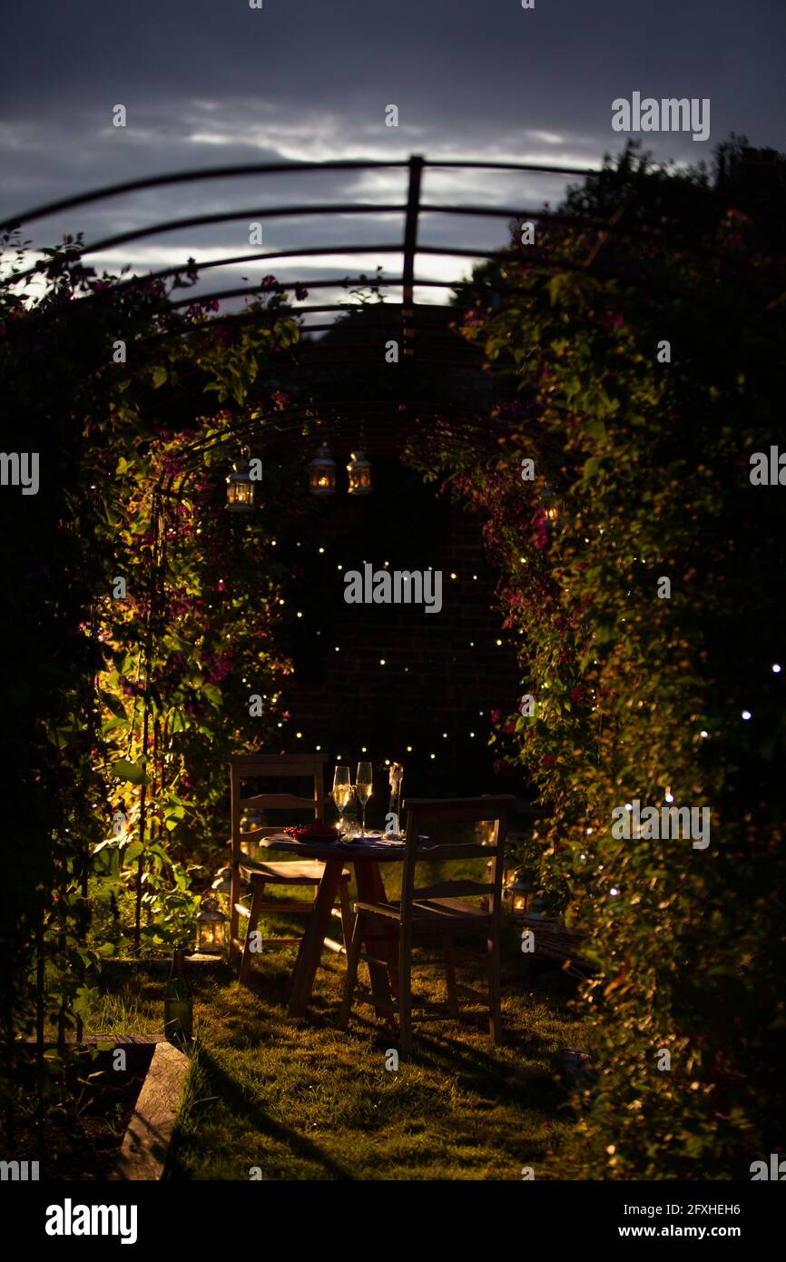 Champagner auf einem idyllischen Sommergartentisch in der Abenddämmerung Stockfoto