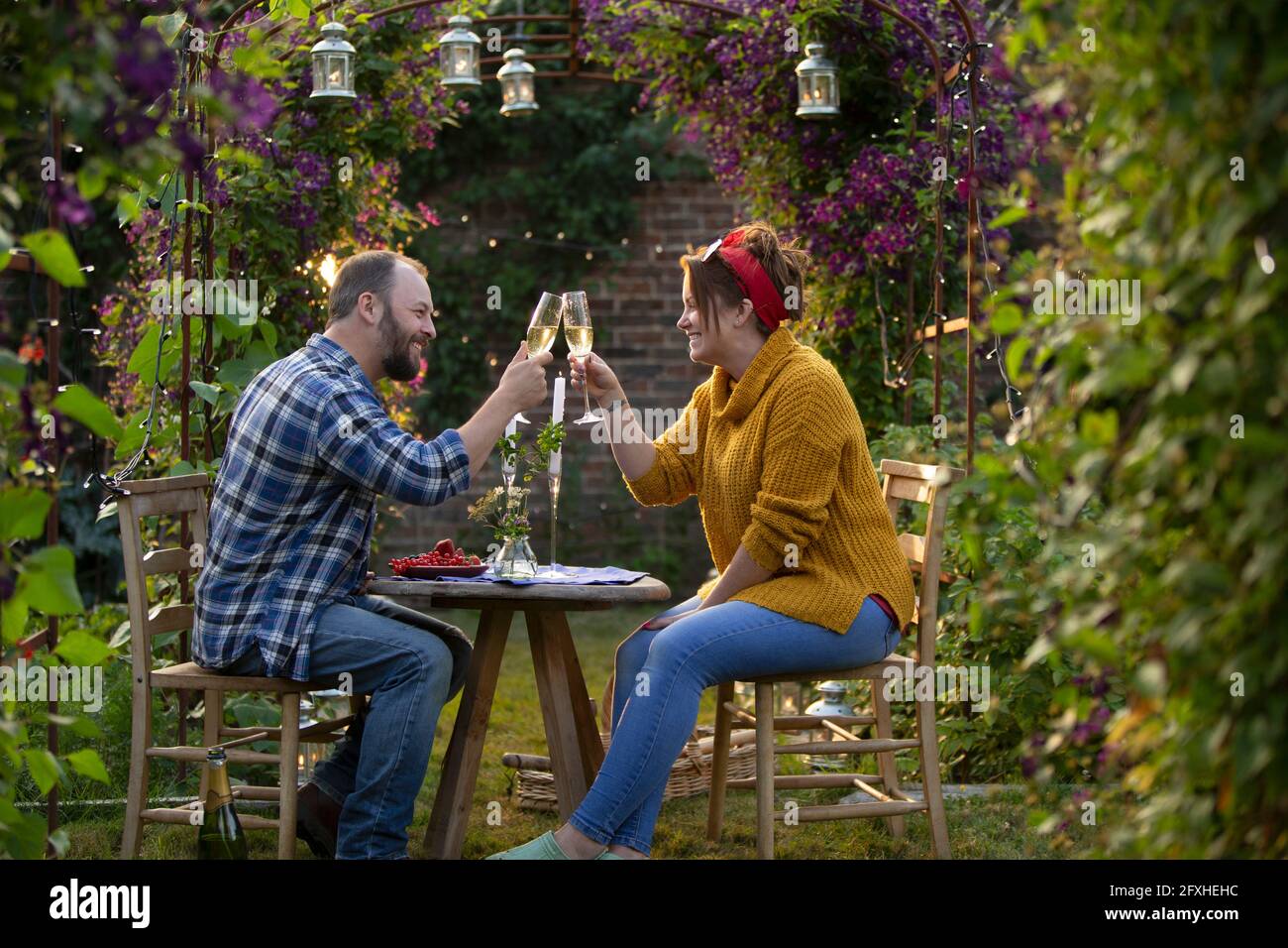 Glückliches Paar, das Champagner im idyllischen Sommergarten toaste Stockfoto