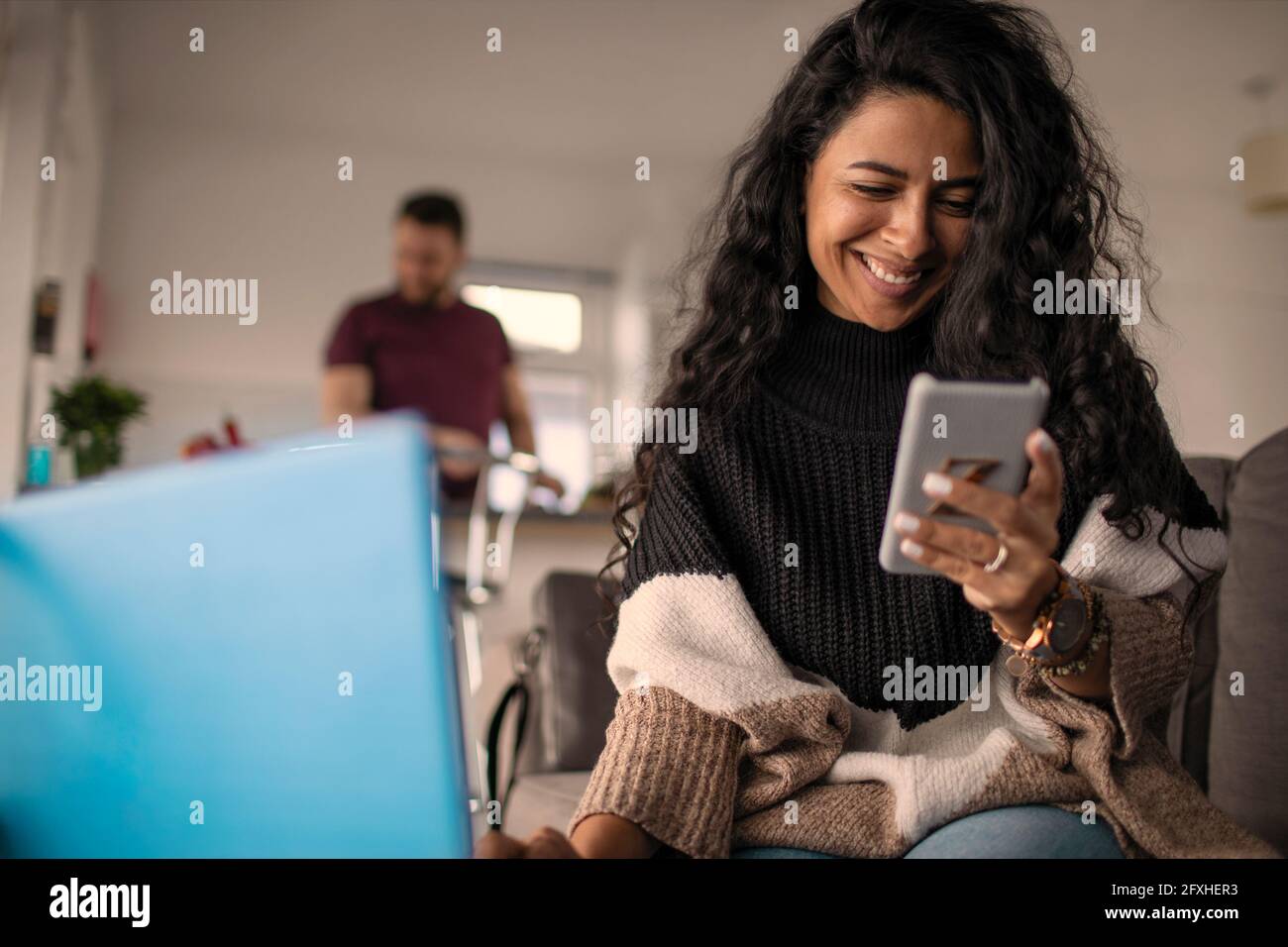 Glückliche Frau, die von zu Hause aus mit einem Laptop und einem Smartphone arbeitet Stockfoto