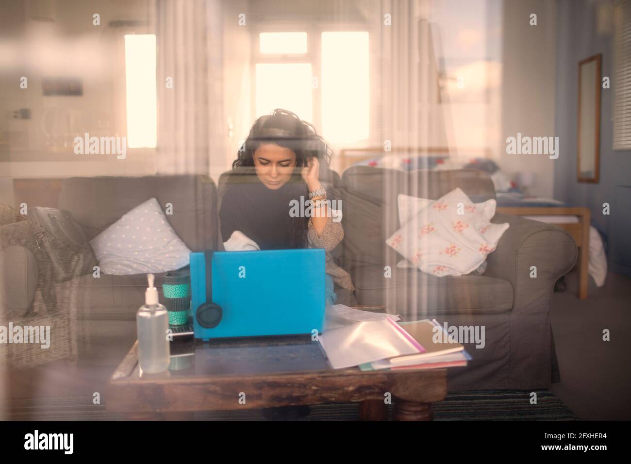 Frau, die von zu Hause aus am Laptop auf dem Sofa im Wohnzimmer arbeitet Stockfoto