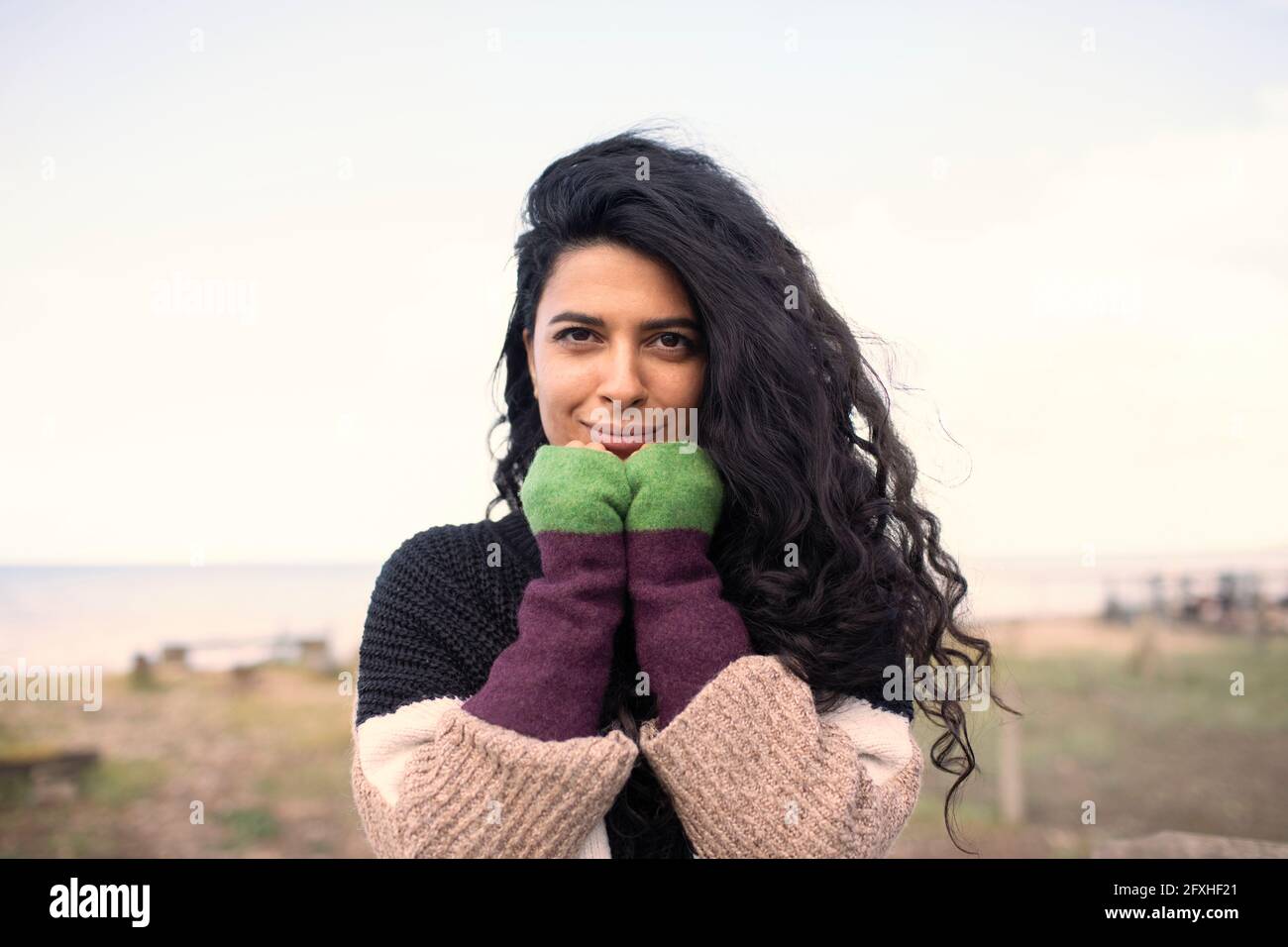 Portrait schöne Frau mit langen lockigen schwarzen Haaren am Strand Stockfoto