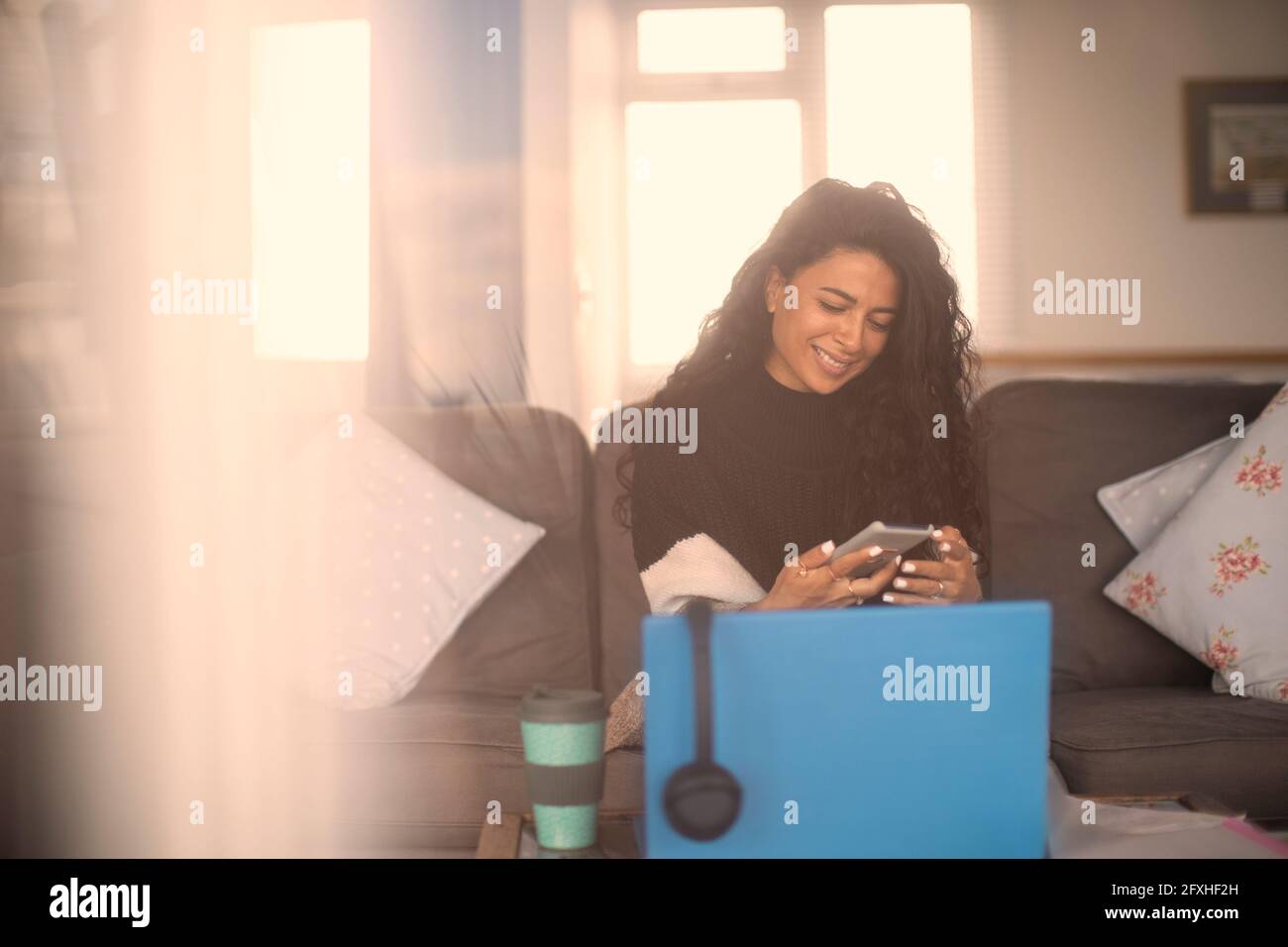 Glückliche Frau, die von zu Hause aus mit Smartphone und Laptop arbeitet Stockfoto